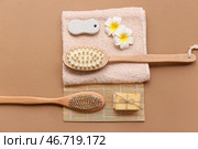 Массажные щетки для тела, бамбуковый коврик, полотенце, цветы плюмерии, пемза и куски мыла на коричневом фоне, крупным планом. Стоковое фото, фотограф Pixel_shot / Фотобанк Лори
