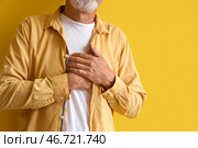Зрелый мужчина испытывает сердечный приступ на жёлтом фоне, крупный план. Стоковое фото, фотограф Pixel_shot / Фотобанк Лори