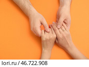 Руки любящей молодой пары с обручальным кольцом на оранжевом фоне. Стоковое фото, фотограф Pixel_shot / Фотобанк Лори