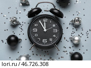 Композиция с черным будильником, украшениями и конфетти на сером фоне. Концепция обратного отсчета до Рождества. Крупный план. Стоковое фото, фотограф Pixel_shot / Фотобанк Лори