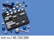 Композиция с киносъемочной хлопушкой, 3D-очками и рождественскими украшениями на синем фоне. Вид сверху. Стоковое фото, фотограф Pixel_shot / Фотобанк Лори
