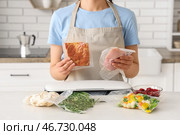 Молодая женщина с вакуумным упаковщиком, мясом и овощами в упаковках на кухонном столе. Стоковое фото, фотограф Pixel_shot / Фотобанк Лори