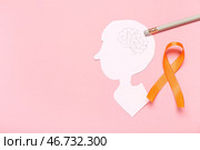 Бумажная голова человека и оранжевая ленточка на розовом фоне. Месяц осведомленности о рассеянном склерозе. Стоковое фото, фотограф Pixel_shot / Фотобанк Лори