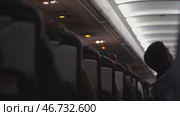 Focus on the ceiling of the passenger plane, where the safety elements, buttons and switches such as the oxygen mask are located. The man pulls himself up on the seat. Стоковое видео, видеограф Darya Komarova / Фотобанк Лори
