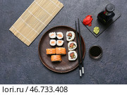 Вкусные суши-роллы с соевым соусом, палочками и бамбуковым ковриком на черном фоне в стиле гранж. Стоковое фото, фотограф Pixel_shot / Фотобанк Лори
