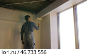 Painter working with paint roller to paint the wall of a room. Стоковое фото, фотограф David Kashakhi / Фотобанк Лори