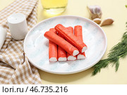 Тарелка с вкусными крабовыми палочками, чесноком и укропом на желтом фоне. Стоковое фото, фотограф Pixel_shot / Фотобанк Лори