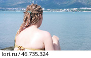Man hands applying sun protection cream on female with african braids on blue sea beach background, protection from sunburn. Стоковое фото, фотограф David Kashakhi / Фотобанк Лори