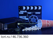 Видеопроектор с киношной хлопушкой, попкорном и киноплёнкой на тёмном фоне. Стоковое фото, фотограф Pixel_shot / Фотобанк Лори