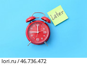 Будильник и стикер с надписью "ПОЗЖЕ" на цветном фоне. Стоковое фото, фотограф Pixel_shot / Фотобанк Лори