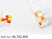 Pillbox by days of the week with fish oil and various pills, on a white background. pillbox for keeping up with your vitamin regimen. Стоковое фото, фотограф Кашапова Эльвира / Фотобанк Лори