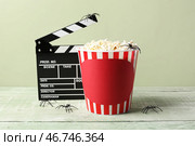 Киношный клюв и ведро с попкорном с пауками на Хэллоуин на деревянном столе на зеленом фоне. Стоковое фото, фотограф Pixel_shot / Фотобанк Лори