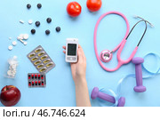 Диабетичка с глюкометром, таблетками, едой, стетоскопом и гантелями на синем фоне. Стоковое фото, фотограф Pixel_shot / Фотобанк Лори