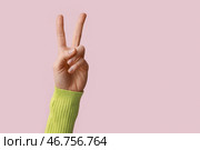 Женская рука, показывающая жест мира на розовом фоне, крупным планом. Стоковое фото, фотограф Pixel_shot / Фотобанк Лори