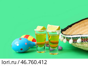 Композиция с маракасами, сомбреро, лаймом и рюмками текилы на зеленом фоне. Стоковое фото, фотограф Pixel_shot / Фотобанк Лори