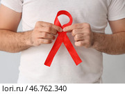 Молодой человек с красной лентой на сером фоне, крупный план. Концепция Всемирного дня борьбы со СПИДом. Стоковое фото, фотограф Pixel_shot / Фотобанк Лори