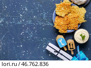 Композиция к Хануке с картофельными блинчиками, сметаной, вращающимися дрейделями и подарочными коробками на тёмно-синем столе. Стоковое фото, фотограф Pixel_shot / Фотобанк Лори