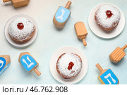 Ханукальная композиция с вкусными пончиками и крутилками на светло-голубом фоне. Стоковое фото, фотограф Pixel_shot / Фотобанк Лори