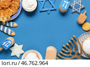 Композиция Ханука с рамкой из меноры, вращающихся вертящихся, пончиков и звезды Давида на голубом фоне. Стоковое фото, фотограф Pixel_shot / Фотобанк Лори