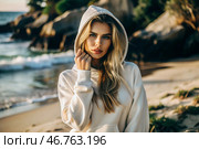 Beautiful young woman in a white hoodie on the beach. Template layout for hoodie design, print area layout for logo or design. Стоковое AI-изображение, AI-художник Photojuli / Фотобанк Лори