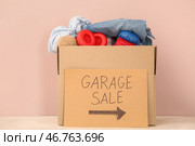 Коробка ненужных вещей для гаражной распродажи на столе возле розовой стены. Стоковое фото, фотограф Pixel_shot / Фотобанк Лори