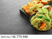 Чаша с вкусным гуакамоле и хлебными чипсами на сером текстурированном фоне. Стоковое фото, фотограф Pixel_shot / Фотобанк Лори