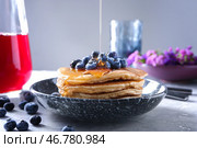 Лить мед на вкусные блины с черникой на светлом столе. Стоковое фото, фотограф Pixel_shot / Фотобанк Лори
