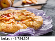 Пергамент с вкусным персиковым галет на темном столе, крупным планом. Стоковое фото, фотограф Pixel_shot / Фотобанк Лори