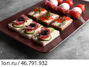 Тарелка с вкусными канапе на сером столе. Стоковое фото, фотограф Pixel_shot / Фотобанк Лори