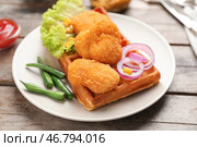 Тарелка с вкусными вафельными и куриными наггетсами на деревянном столе. Стоковое фото, фотограф Pixel_shot / Фотобанк Лори
