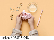 Женщина полирует красивое кольцо салфеткой на цветном фоне, крупным планом. Стоковое фото, фотограф Pixel_shot / Фотобанк Лори