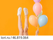 Женские ноги с развязанными шнурками на обуви и воздушными шариками на желтом фоне. Стоковое фото, фотограф Pixel_shot / Фотобанк Лори