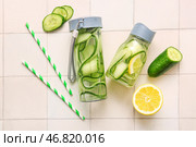 Спортивные бутылки с водой с огуречными ломтями на фоне белой плитки. Стоковое фото, фотограф Pixel_shot / Фотобанк Лори
