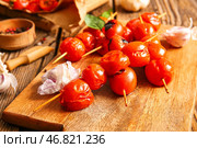 Доска со шпажками с вкусными жареными помидорами и базиликом на деревянном фоне. Стоковое фото, фотограф Pixel_shot / Фотобанк Лори