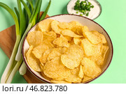 Миска вкусной сметаны с нарезанным луком-пореем и картофельными чипсами на зеленом фоне. Стоковое фото, фотограф Pixel_shot / Фотобанк Лори