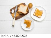 Доска и тарелки с вкусными грилями, абрикосовым джемом и ножом на белом деревянном фоне. Стоковое фото, фотограф Pixel_shot / Фотобанк Лори