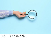 Женская рука с увеличителем на синем фоне. Стоковое фото, фотограф Pixel_shot / Фотобанк Лори
