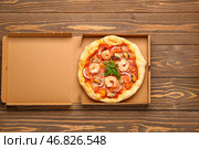 Картонная коробка с вкусной пиццей из морепродуктов на деревянном фоне. Стоковое фото, фотограф Pixel_shot / Фотобанк Лори
