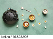 Чайник с чашками натурального ромашкового чая, кусочками сахара и цветами на зеленом грунтовом фоне. Стоковое фото, фотограф Pixel_shot / Фотобанк Лори