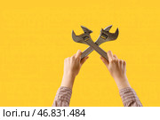 Женская рука, держащая регулируемые гаечные ключи на желтом фоне. Стоковое фото, фотограф Pixel_shot / Фотобанк Лори