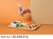 Женская рука с палочками, китайскими пельменями, тофу-сыром и соевым соусом на цветном фоне. Стоковое фото, фотограф Pixel_shot / Фотобанк Лори
