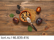 Миска с вареной овсянкой и черносливом на деревянном фоне. Стоковое фото, фотограф Pixel_shot / Фотобанк Лори