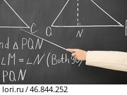 Женская учительница с указывающим устройством объясняет математические формулы на доске. Стоковое фото, фотограф Pixel_shot / Фотобанк Лори