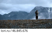 Man photographing mountain highness landscape. Clip. Rear view of a man hiker taking photos of heavy clouds and mountain tops. Стоковое фото, фотограф Данил Руденко / Фотобанк Лори