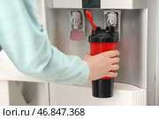 Женская рука наполняет бутылку фильтрованной водой из кулера в комнате. Стоковое фото, фотограф Pixel_shot / Фотобанк Лори
