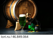 Стакан зелёного пива с бочкой, горшком полным монет, подковой и клеверным листом на черном фоне. Празднование Дня святого Патрика. Стоковое фото, фотограф Pixel_shot / Фотобанк Лори
