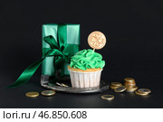 Вкусный кекс в подарочной коробке, подкова и золотые монеты к Дню святого Патрика на черном фоне. Стоковое фото, фотограф Pixel_shot / Фотобанк Лори