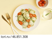 Тарелка вкусных равиоли и стакан с водой на жёлтом фоне. Стоковое фото, фотограф Pixel_shot / Фотобанк Лори
