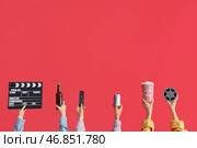 Множество рук с ведром попкорна, кинематографическим хлопушкой и пивом на красном фоне. Стоковое фото, фотограф Pixel_shot / Фотобанк Лори