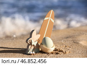 Игрушечный кролик, доска для серфинга и разукрашенное пасхальное яйцо на морском пляже. Стоковое фото, фотограф Pixel_shot / Фотобанк Лори